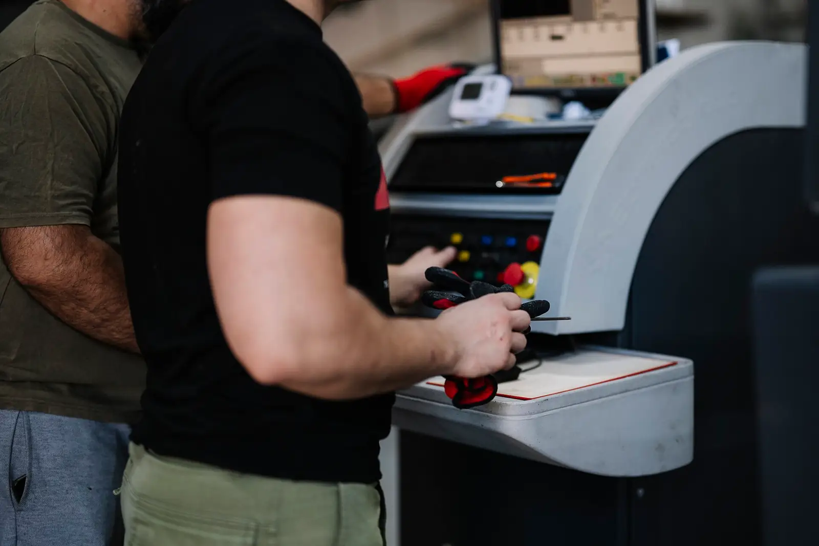 Fabrikada makine kontrol paneli başında çalışan iki kişi